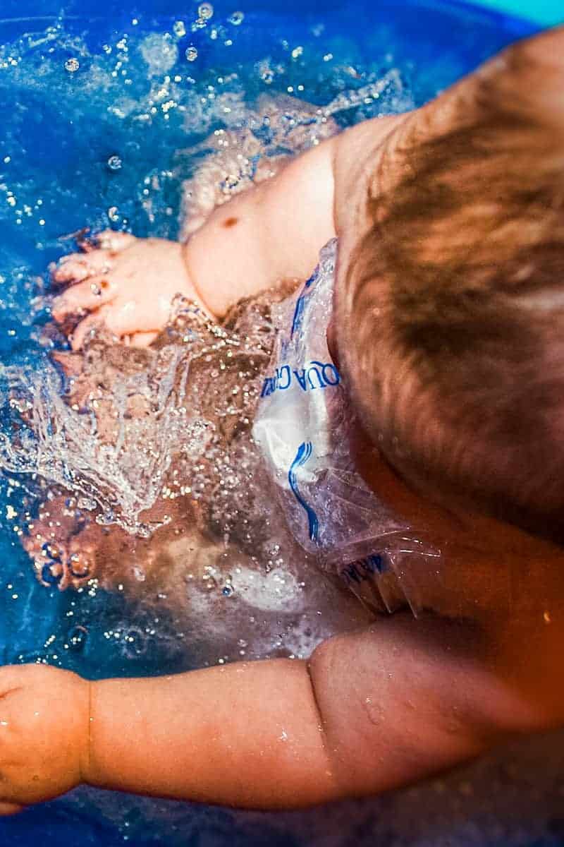 Baby splashing in water with AquaGuard covering Broviac line