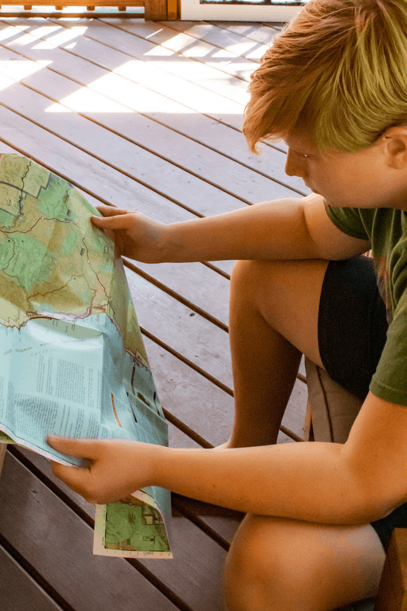 Kid sitting and reading a map - how to teach kids about maps