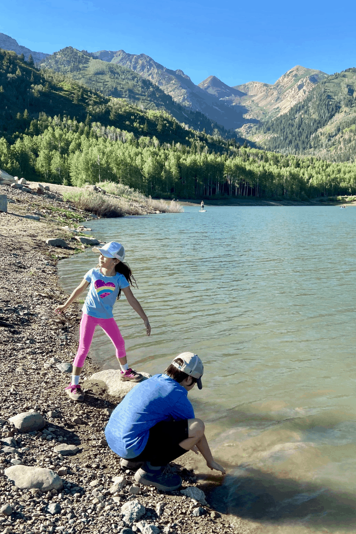 Children playing with rocks at a lake in the mountains