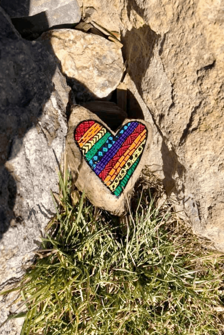 A rainbow painted rock with beautiful intricate designs. 