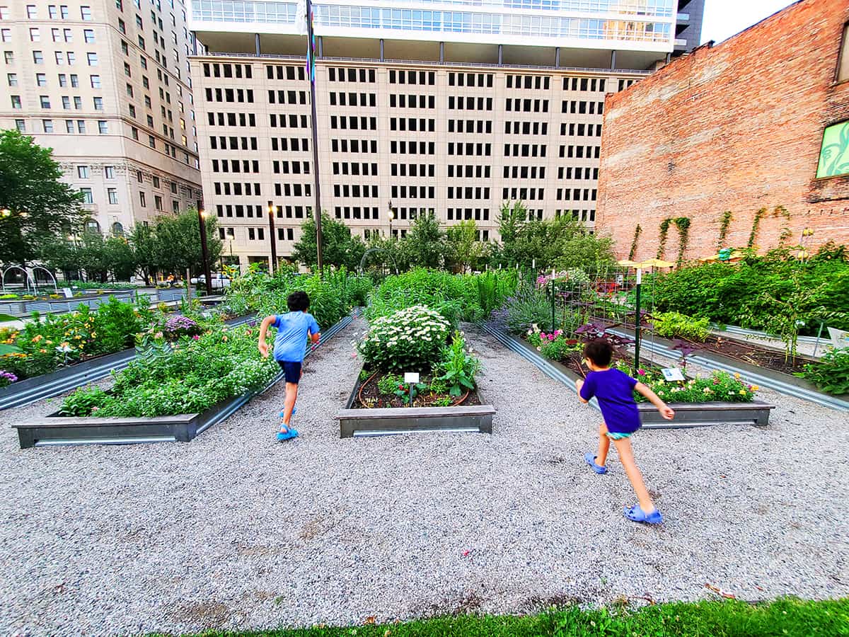 2 kids running through a community garden in Detroit, MI - getting kids outside in the city