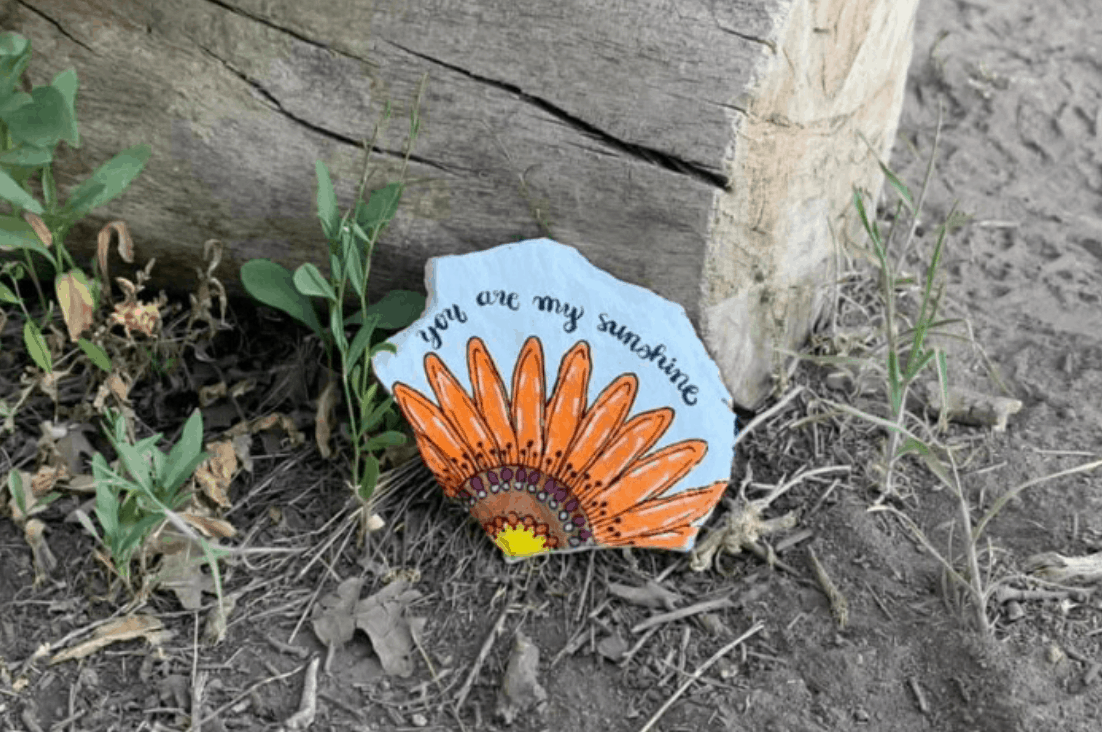 A painted rock with a sunflower that reads 