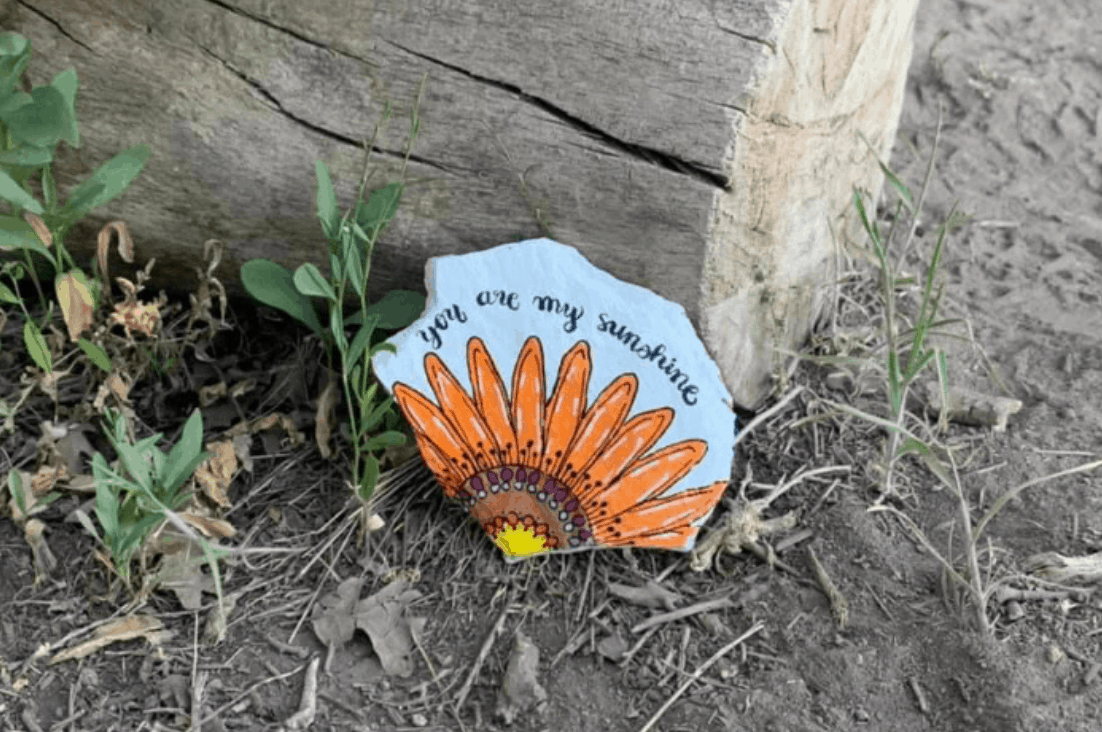 A painted rock with a sunflower that reads "You are my sunshine"