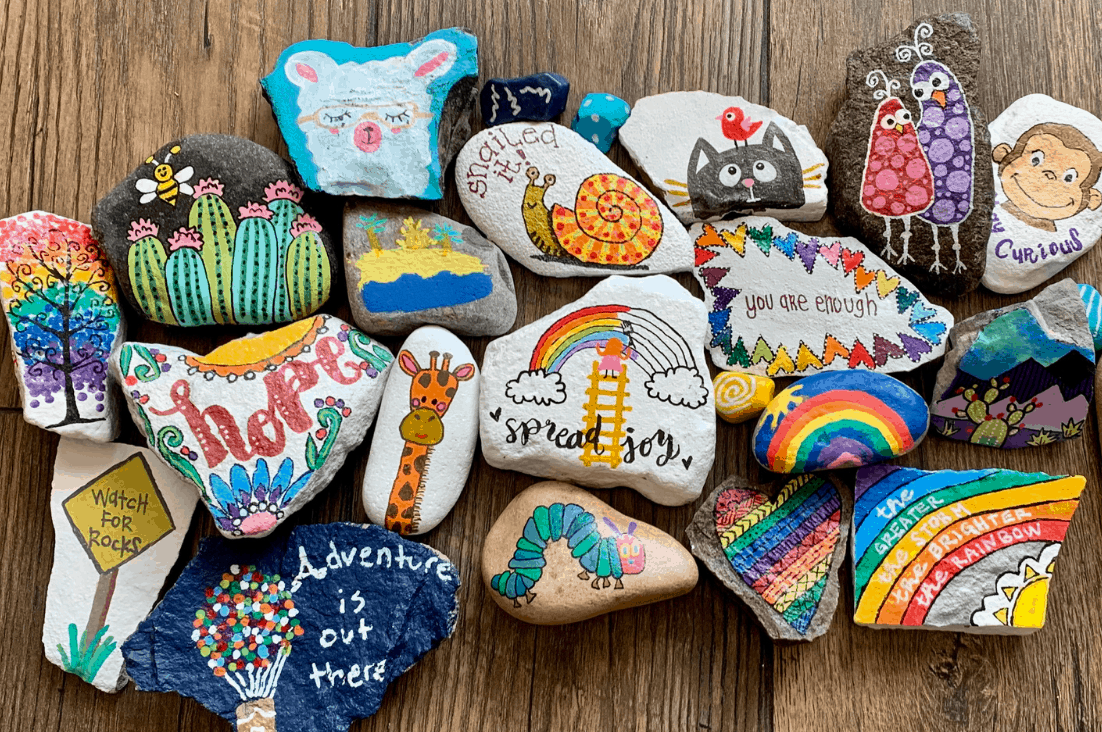colorful rock art painted in a variety of colors, rainbows, mountains curious george and Bluey