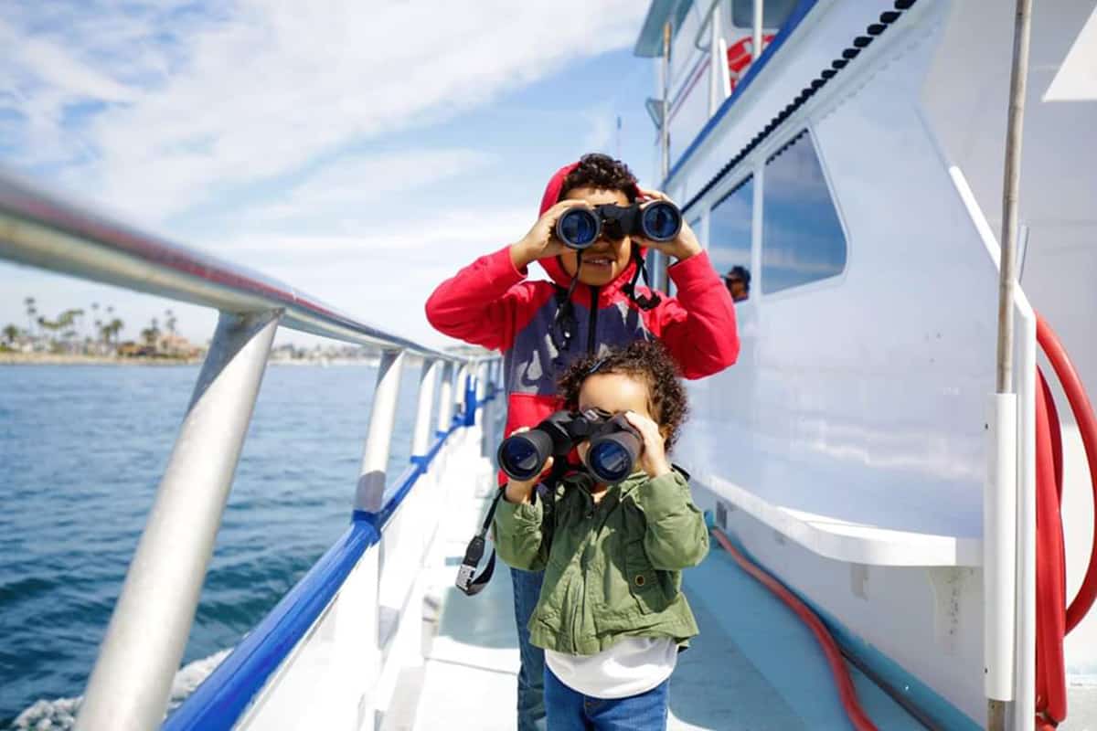 two kids on a boat with binoculars - best outdoor activities and adventures for kids