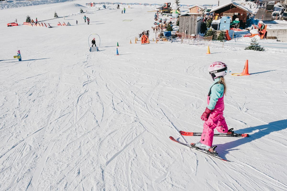 a child stands in a snowplough while learning to downhill ski