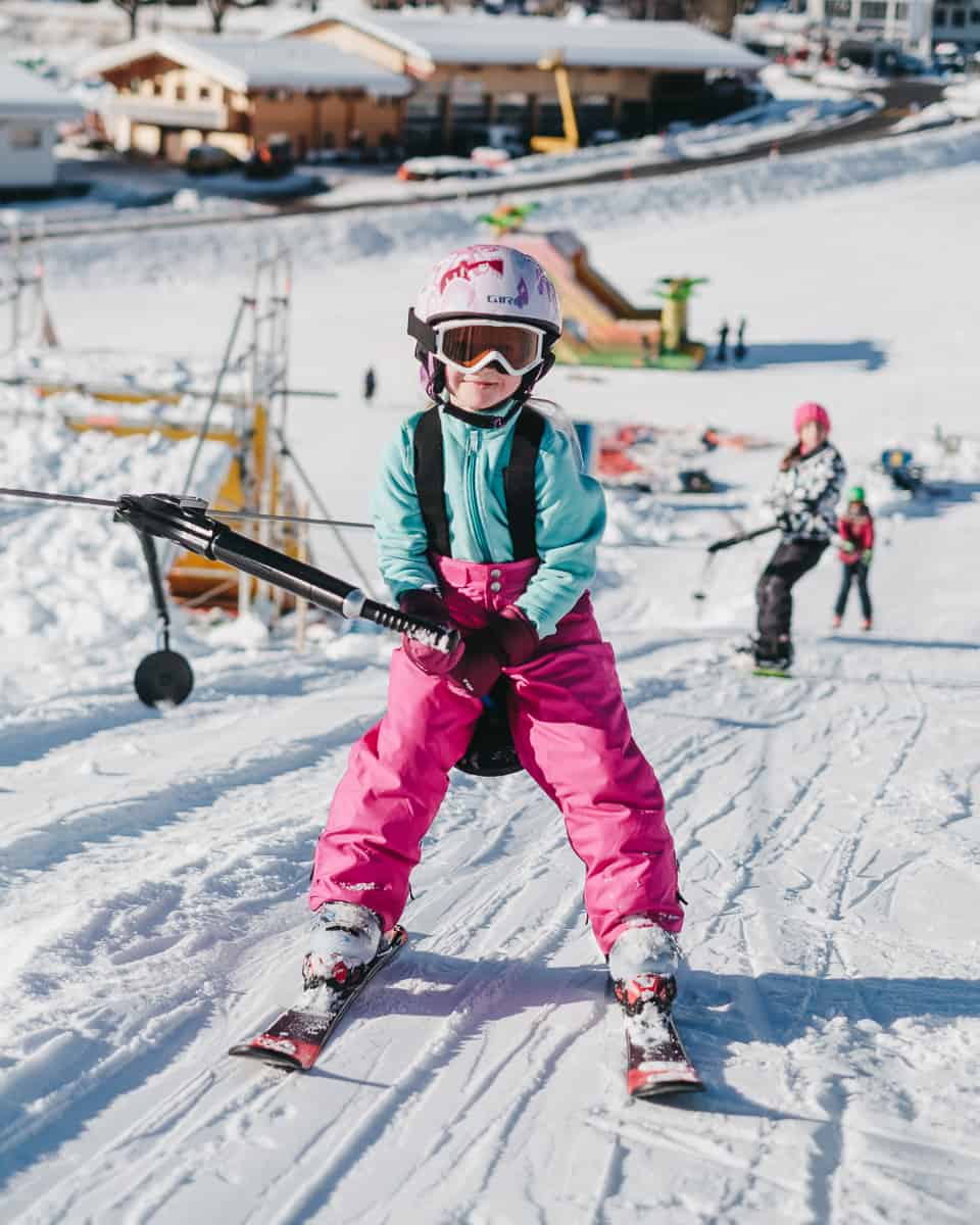 child on a ski lift smiling as she learns to ski