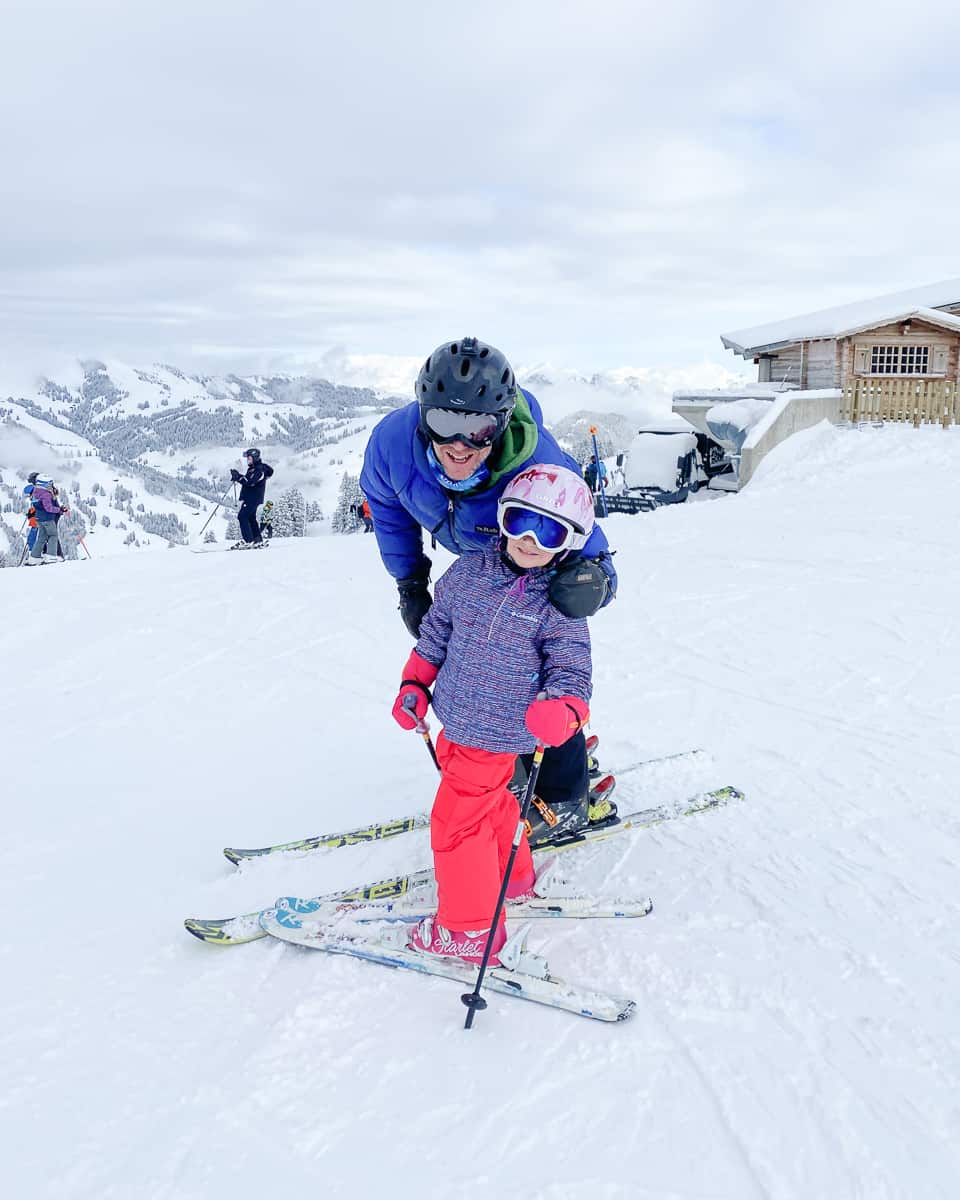 a father and child on a ski slope learning to downhill ski