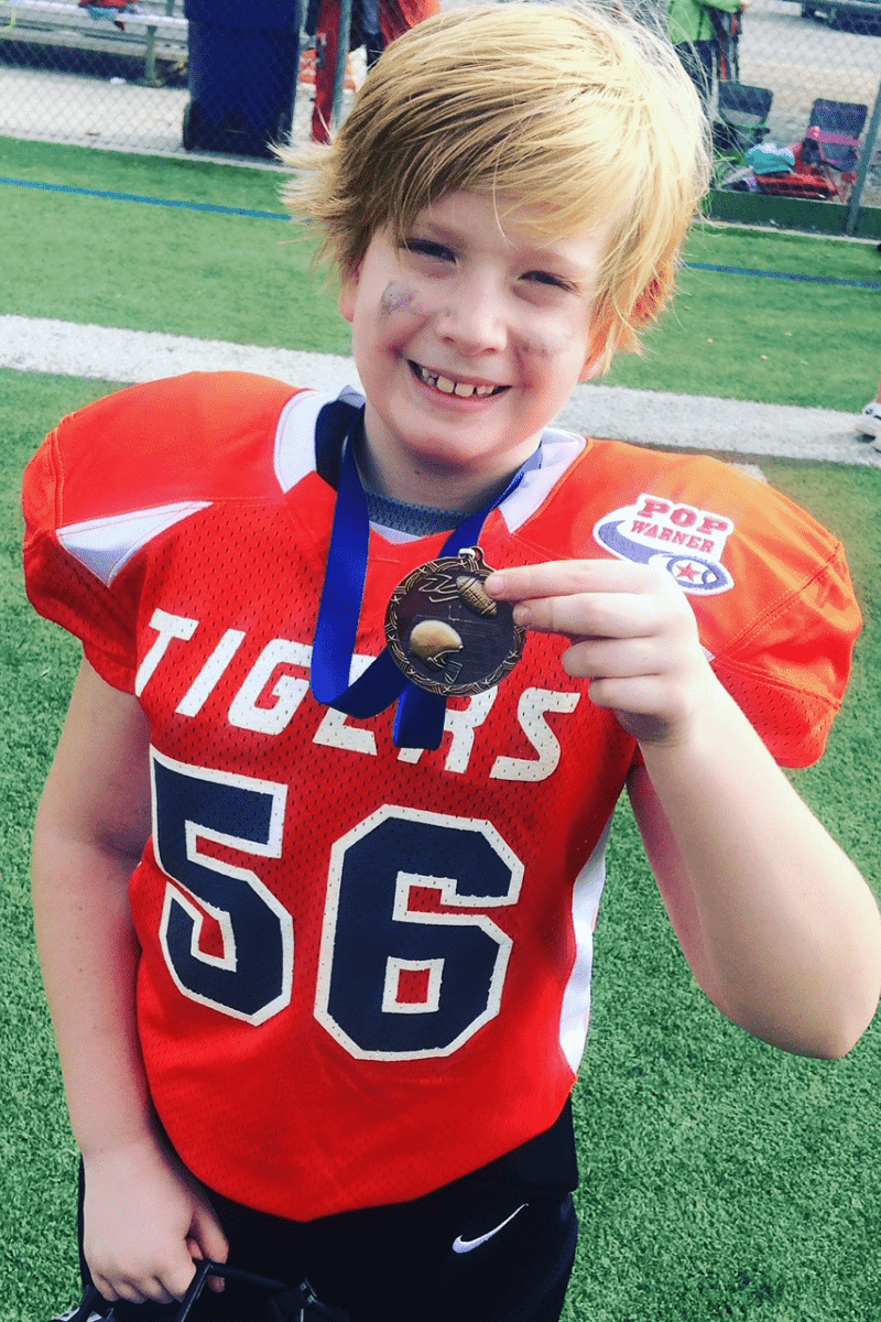 young boy in football uniform with a medal