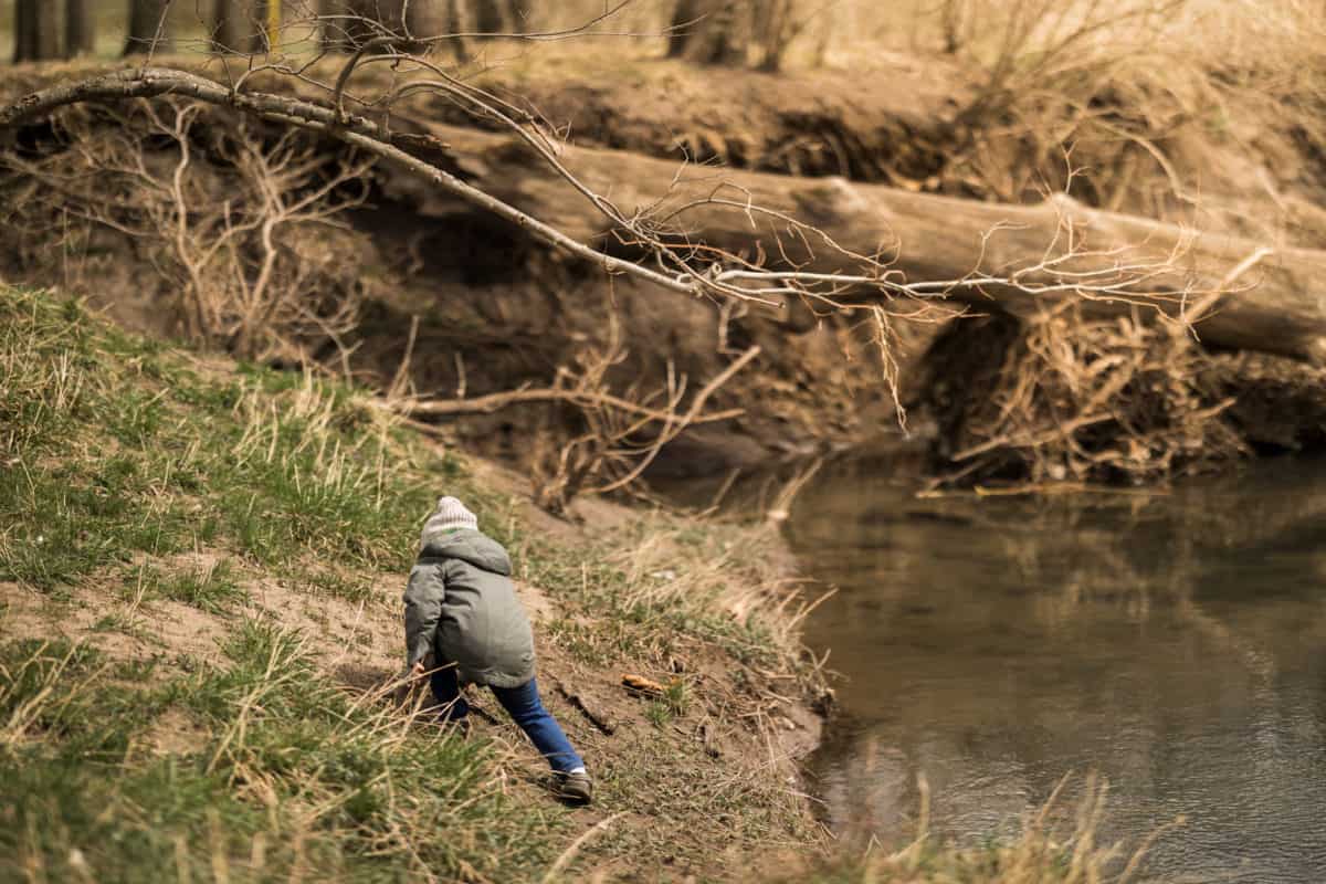 Child searching ground along creek bed