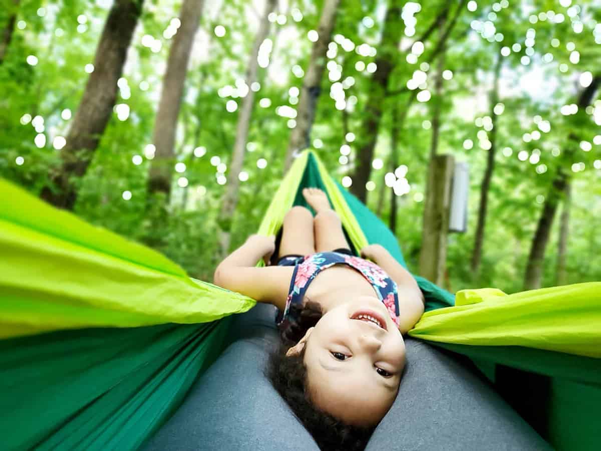 A girl swinging upside down in a hammock on her mother's legs.