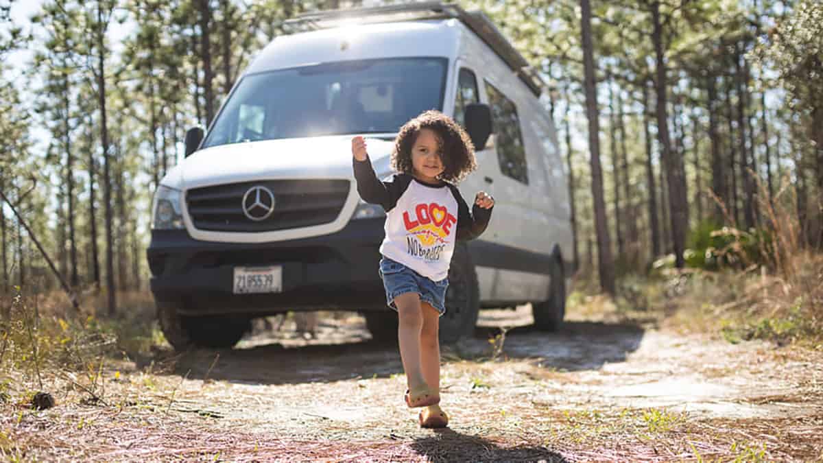 A child dancing in front of her campervan.