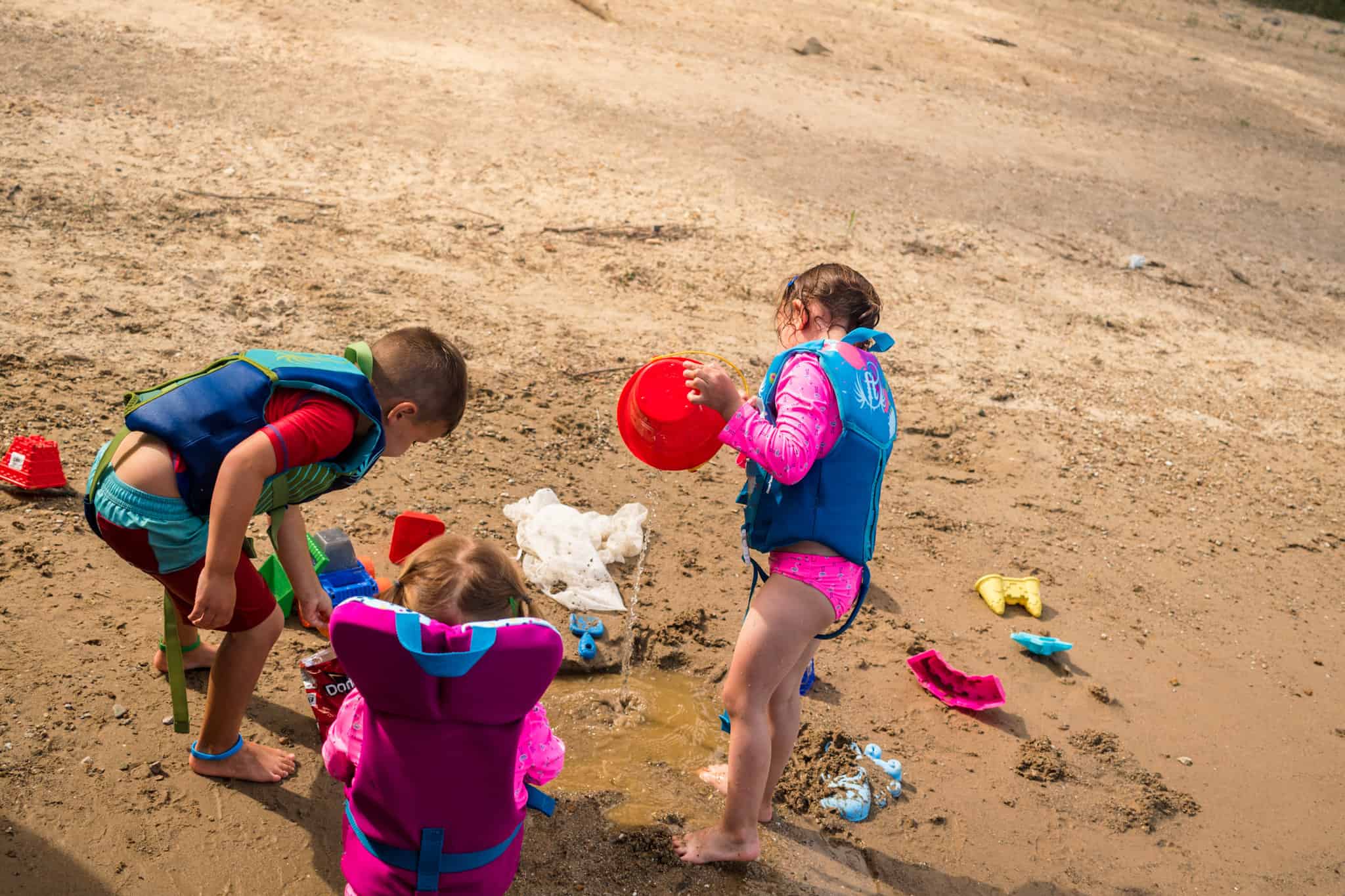 Children playing in sand with life jackets on - how to choose the best life jacket for kids