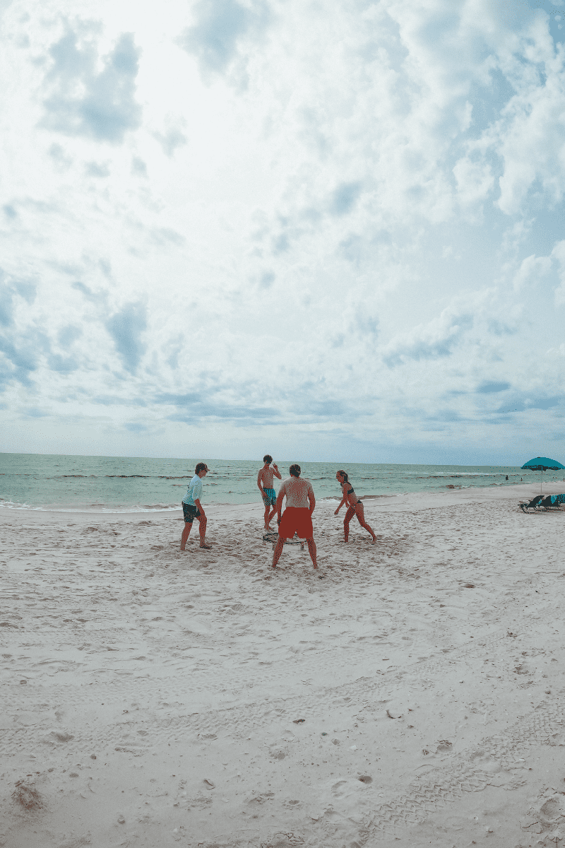 family playing spikeball on a whilte sand beach on Cape San Blas