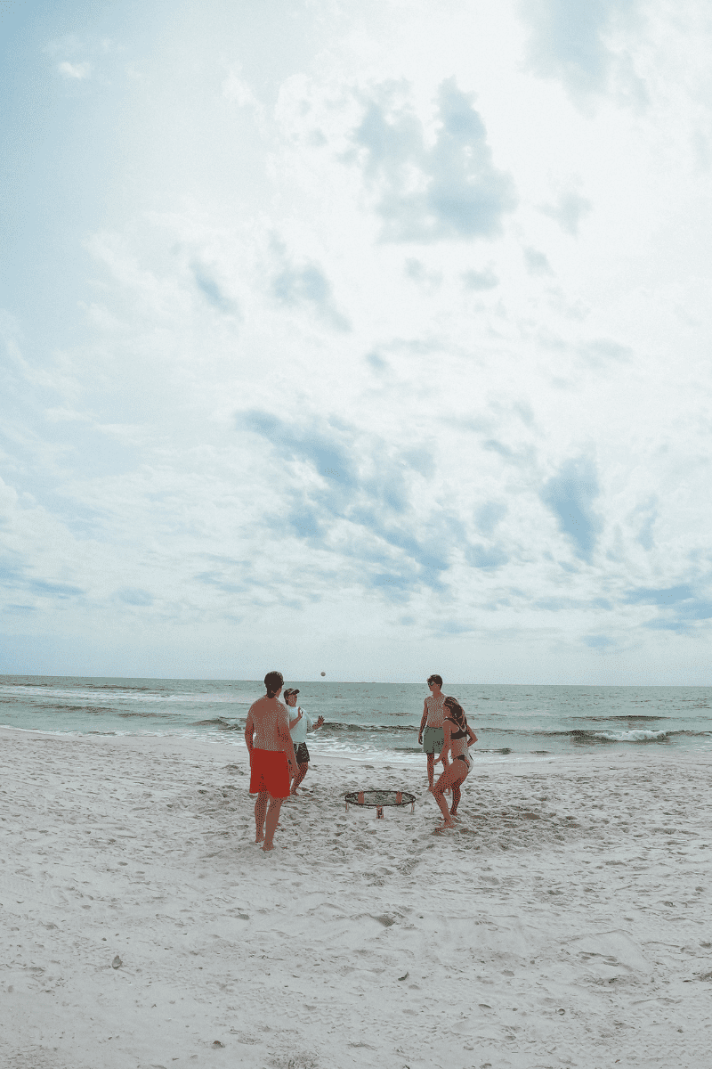 Family playing spikeball on a white sand beach while on vacation in Gulf County Florida