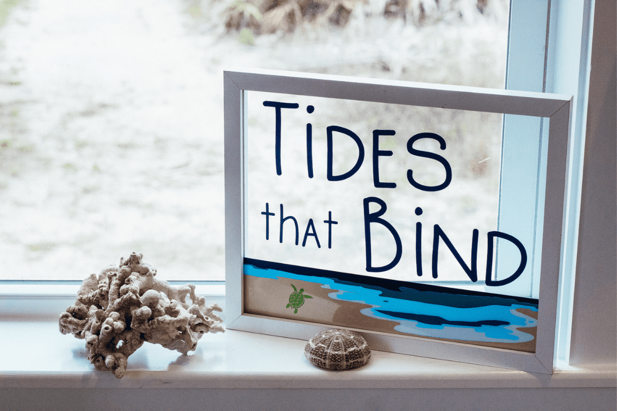 Home decor sign that reads Tides that Bind with two seashells in front of it