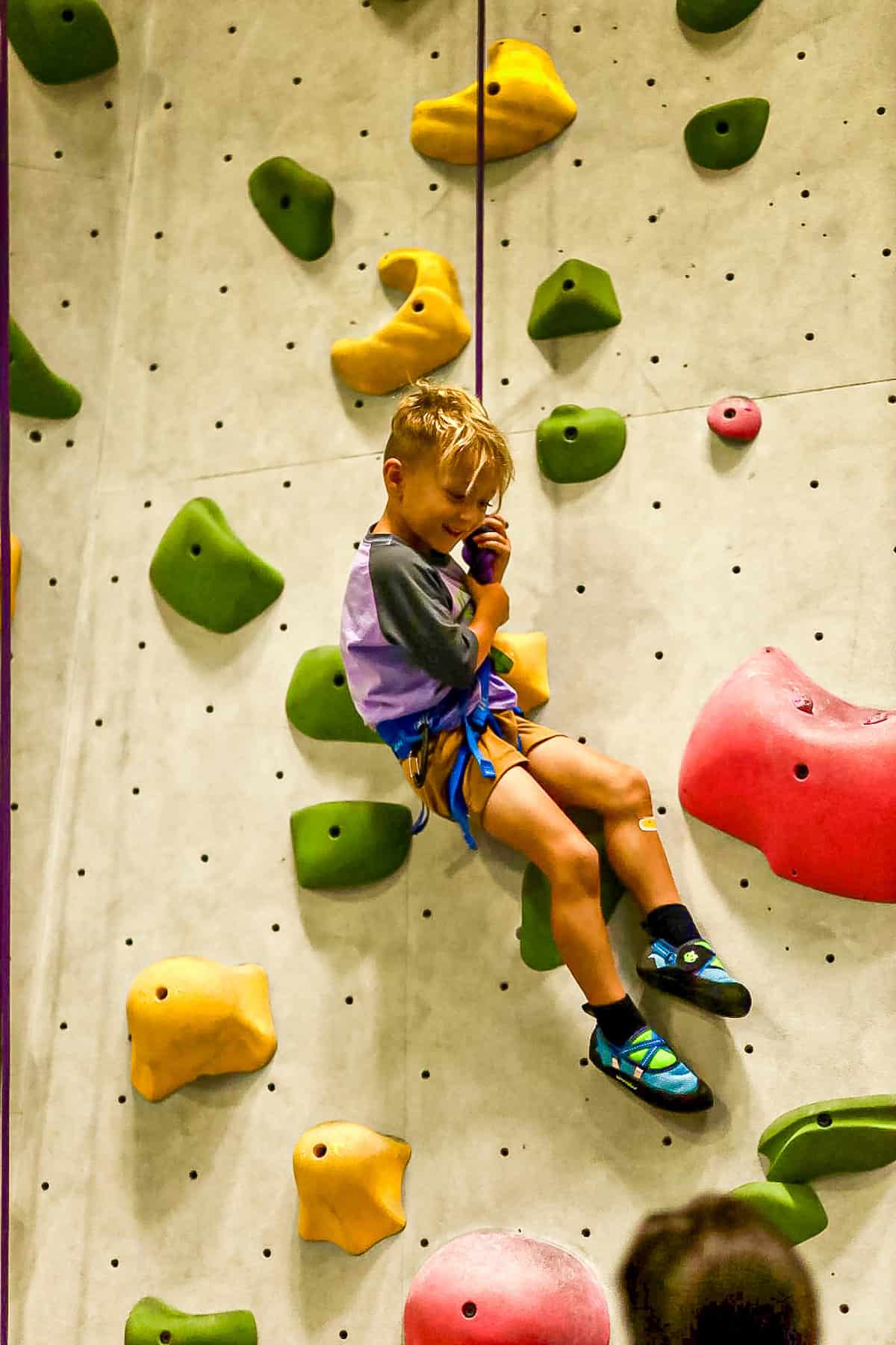 young rock climber descending a climbing wall