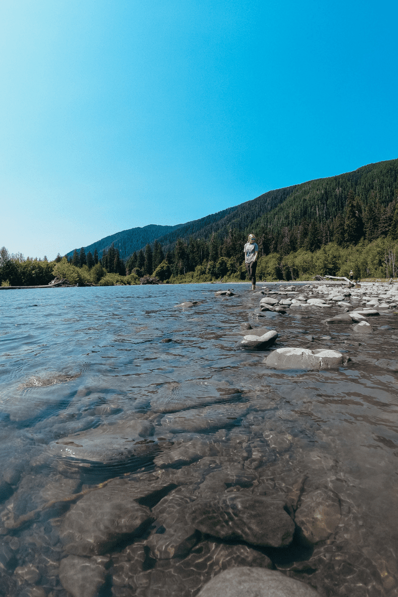 teen girl walking in the shallow river bed inside olympic national park
