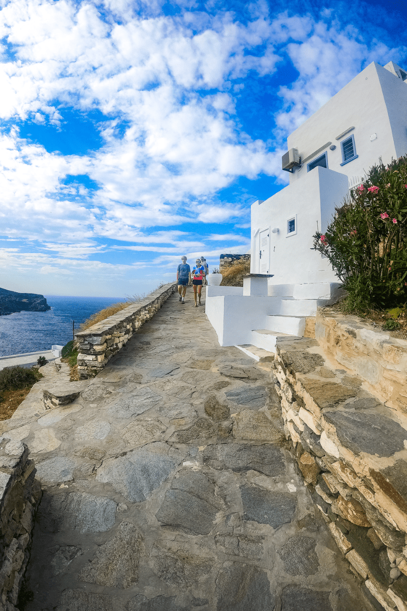 3 teens walking on a coastal walkway on the island of sifnos in greece