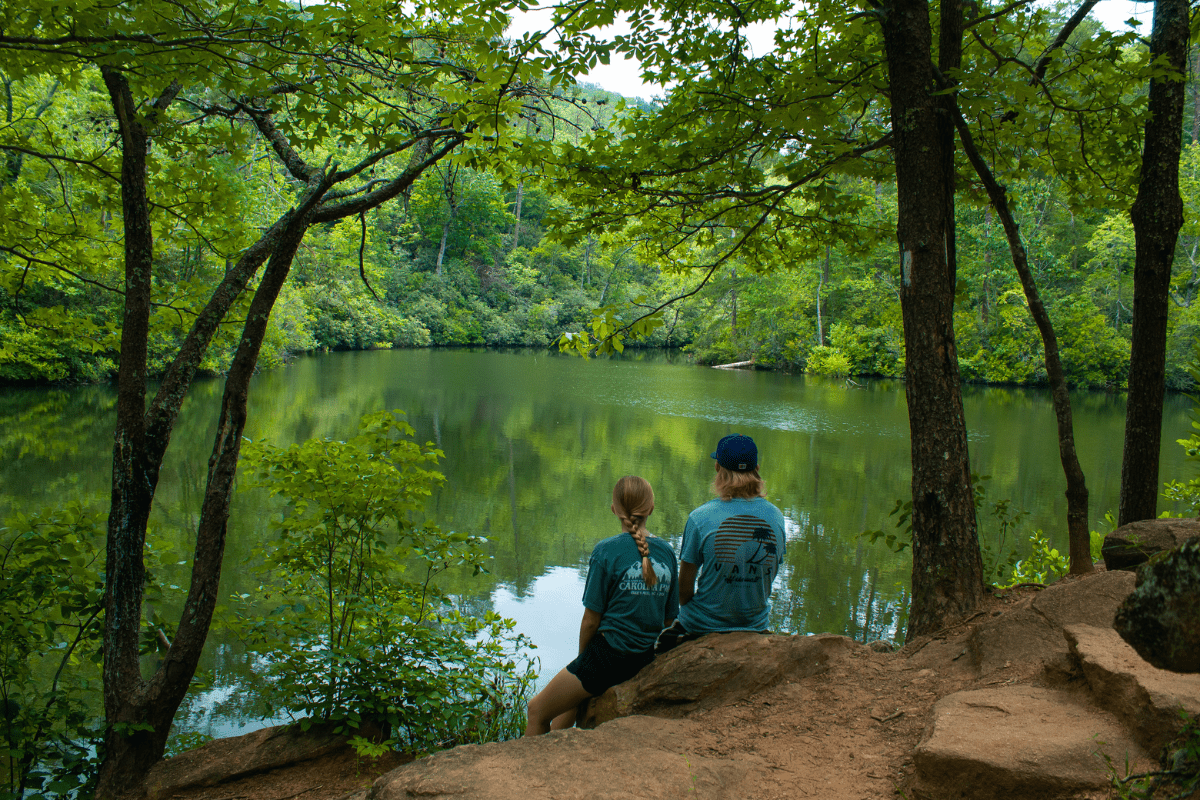 two teens sitting down above a lake in Paris Mountain SC state park