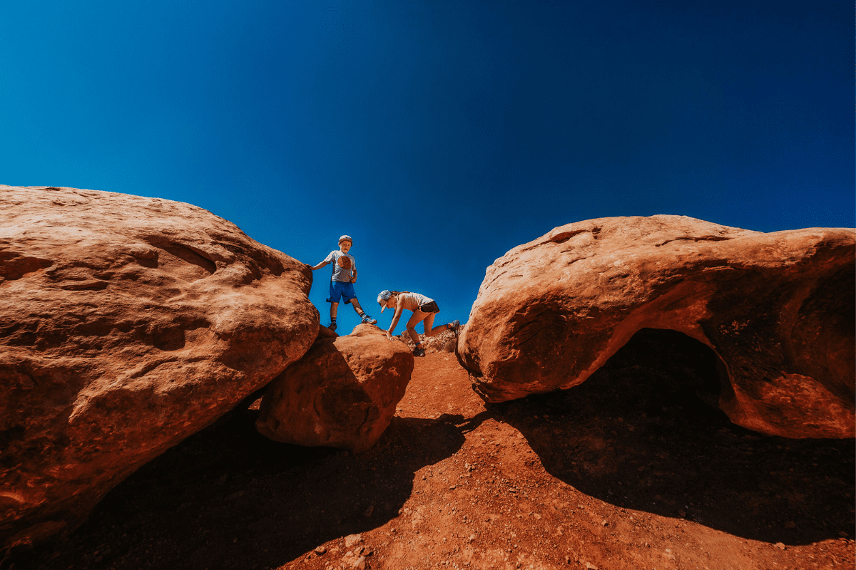 two kids scrambling on rock formations in Moab