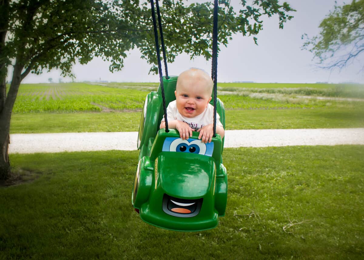 Baby in a green tractor swing