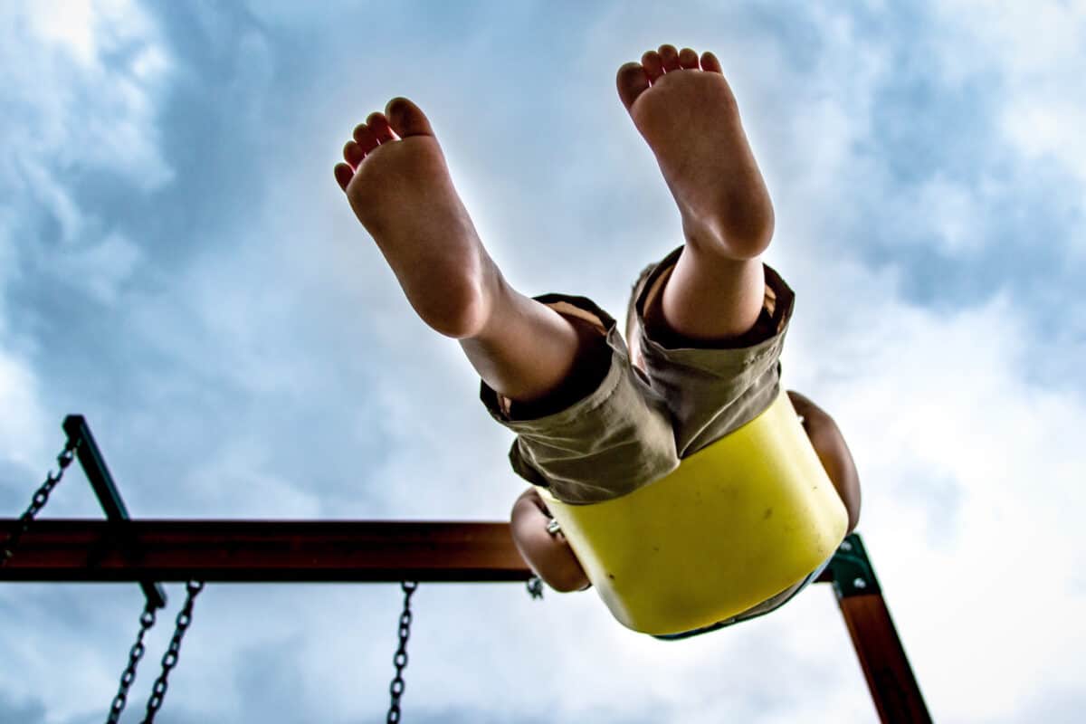 Ground up point of view of child swinging
