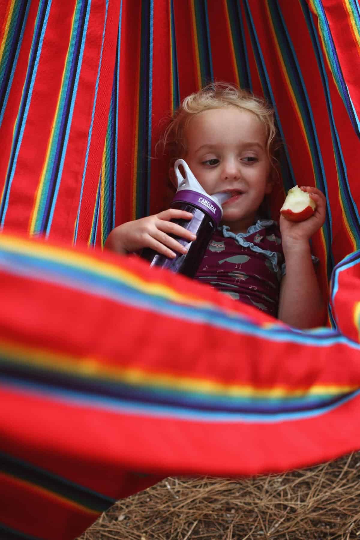 Girl In hammock swing eating apple