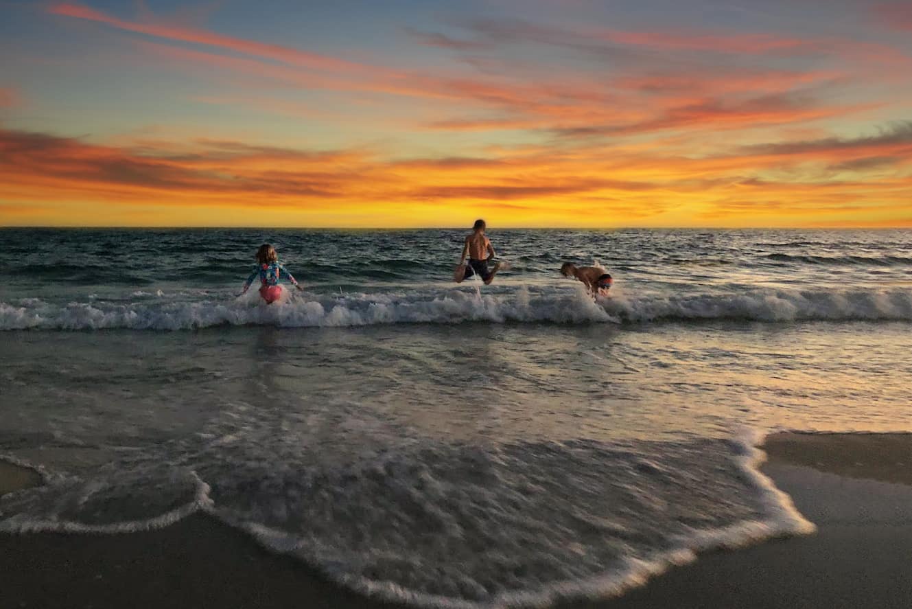 sunsets on the beach in destin - kids playing in the waves