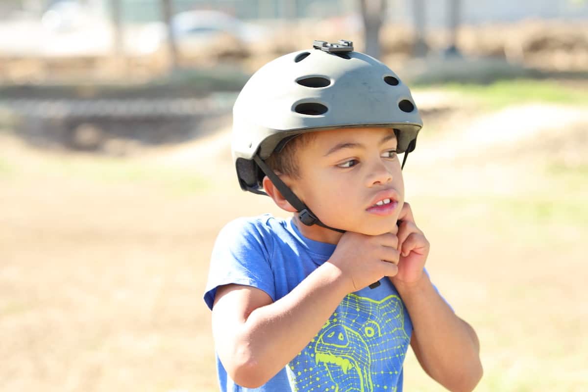 kid putting on a bike helmet - best mountain bikes for kids