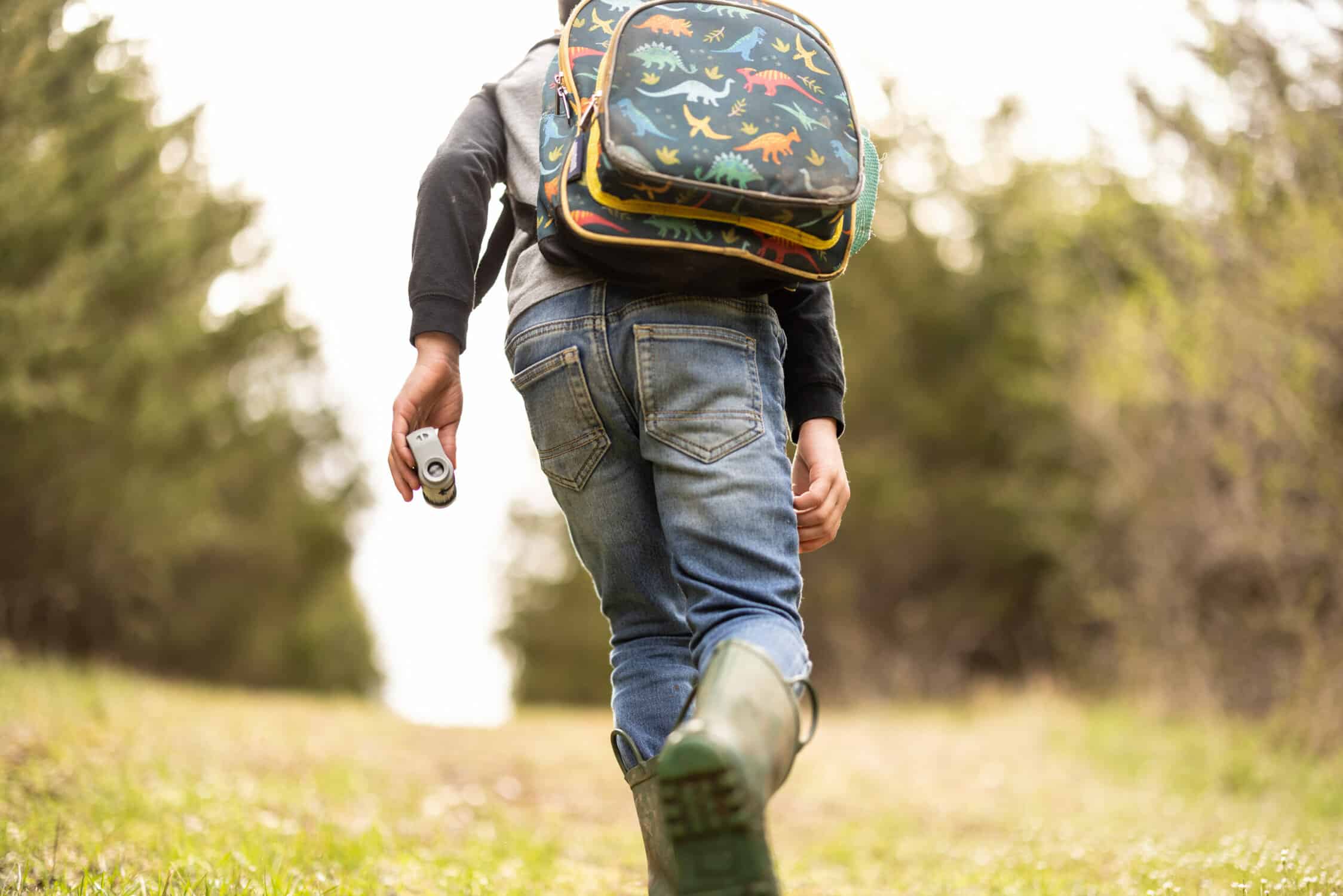 child hiking with backpack and microscope