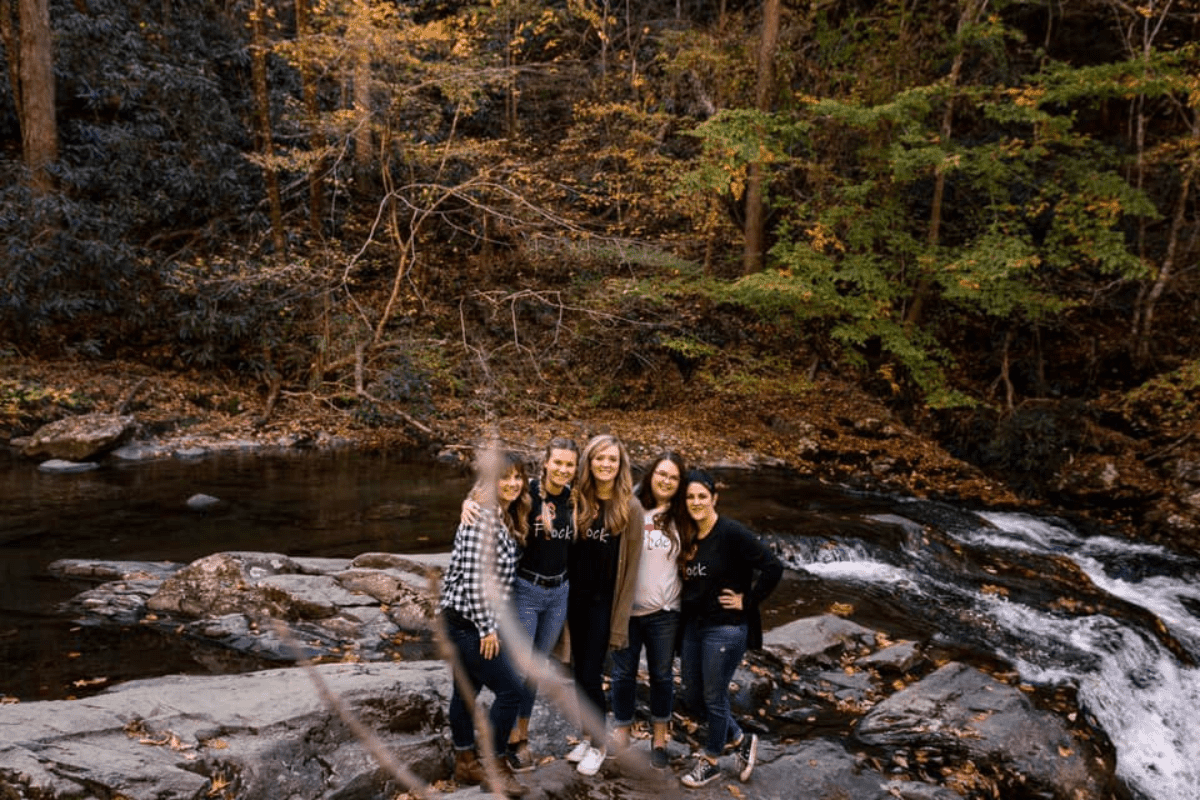 A group of adventure friends standing next to a river in a forest. 
