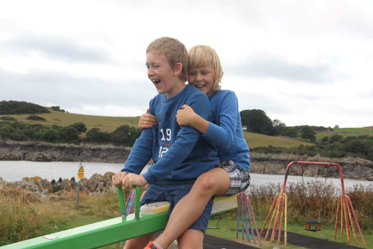 two boys on a seesaw laughing
