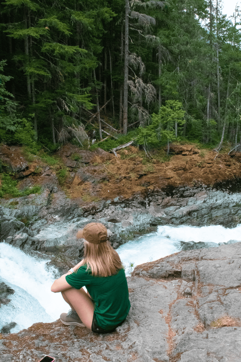 teen girl sitting on the edge of a waterfall