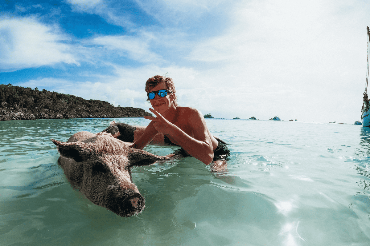 teen boy swimming with a pig in Exuma, Bahamas