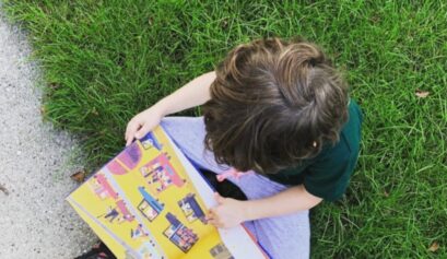Child reading outside in the grass, seen from above