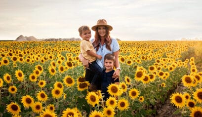 A woman and her children pose for a photo in a vast sunflower field.