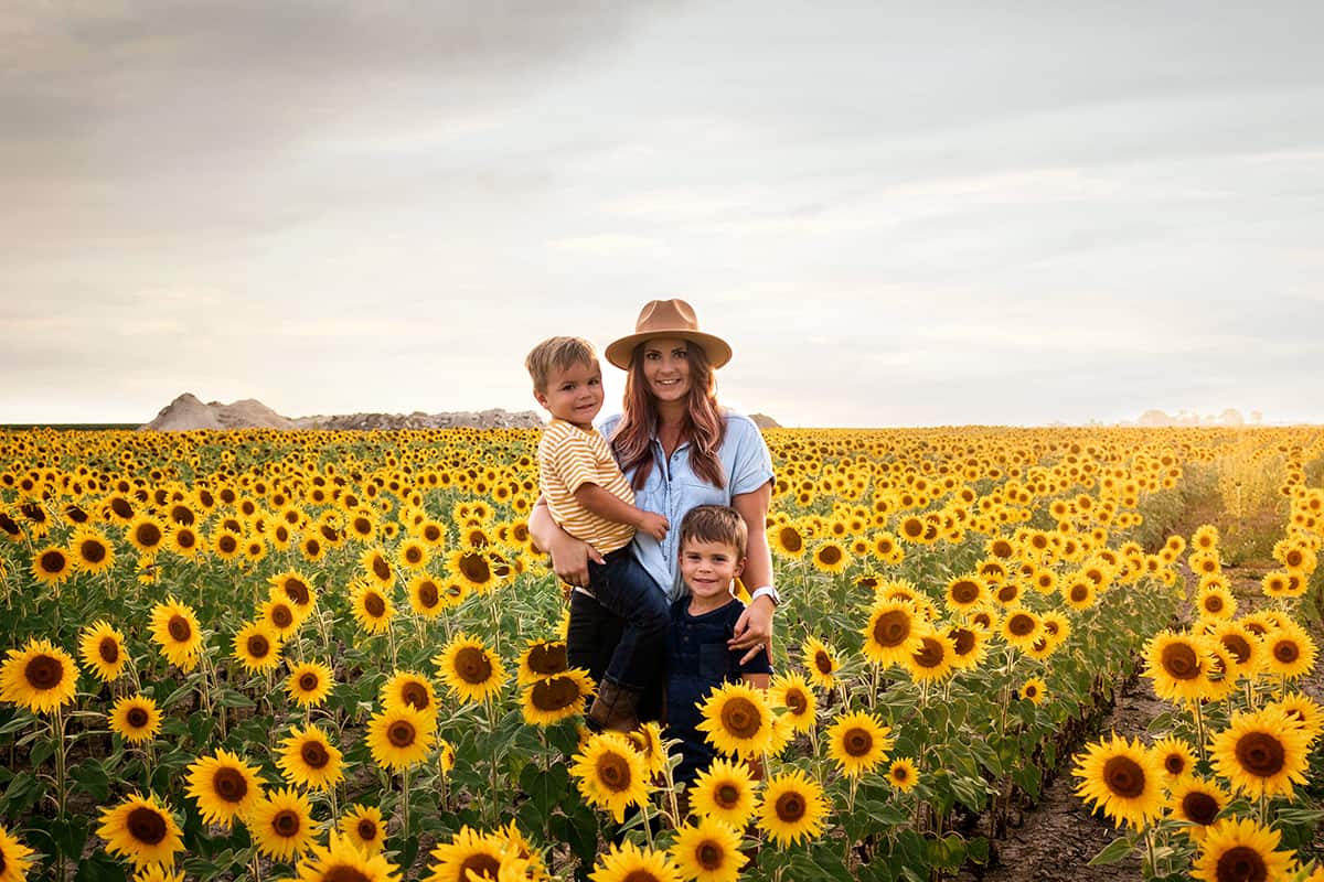 A woman poses in a vast sunflower field with her family.