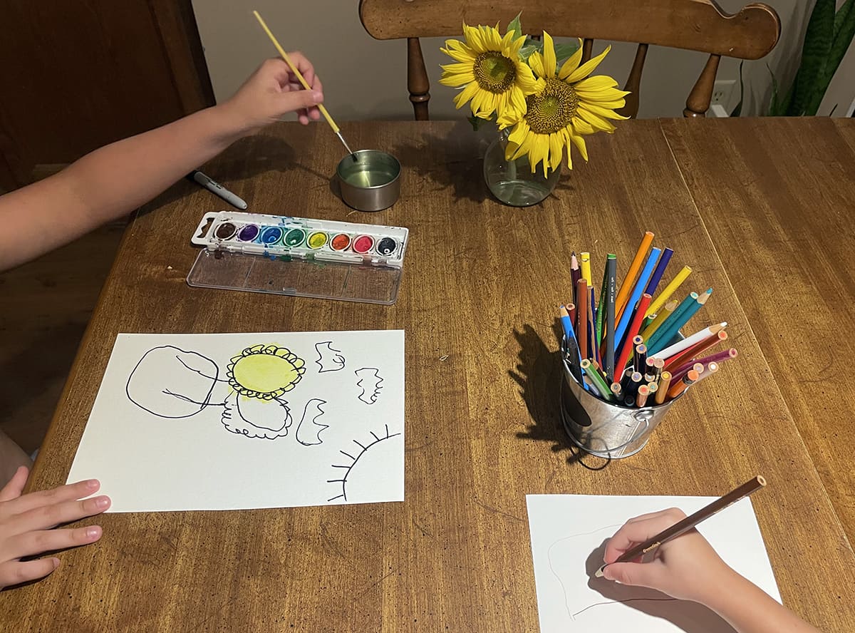 Two children create portraits of sunflowers they picked from the field while visiting with their family. 