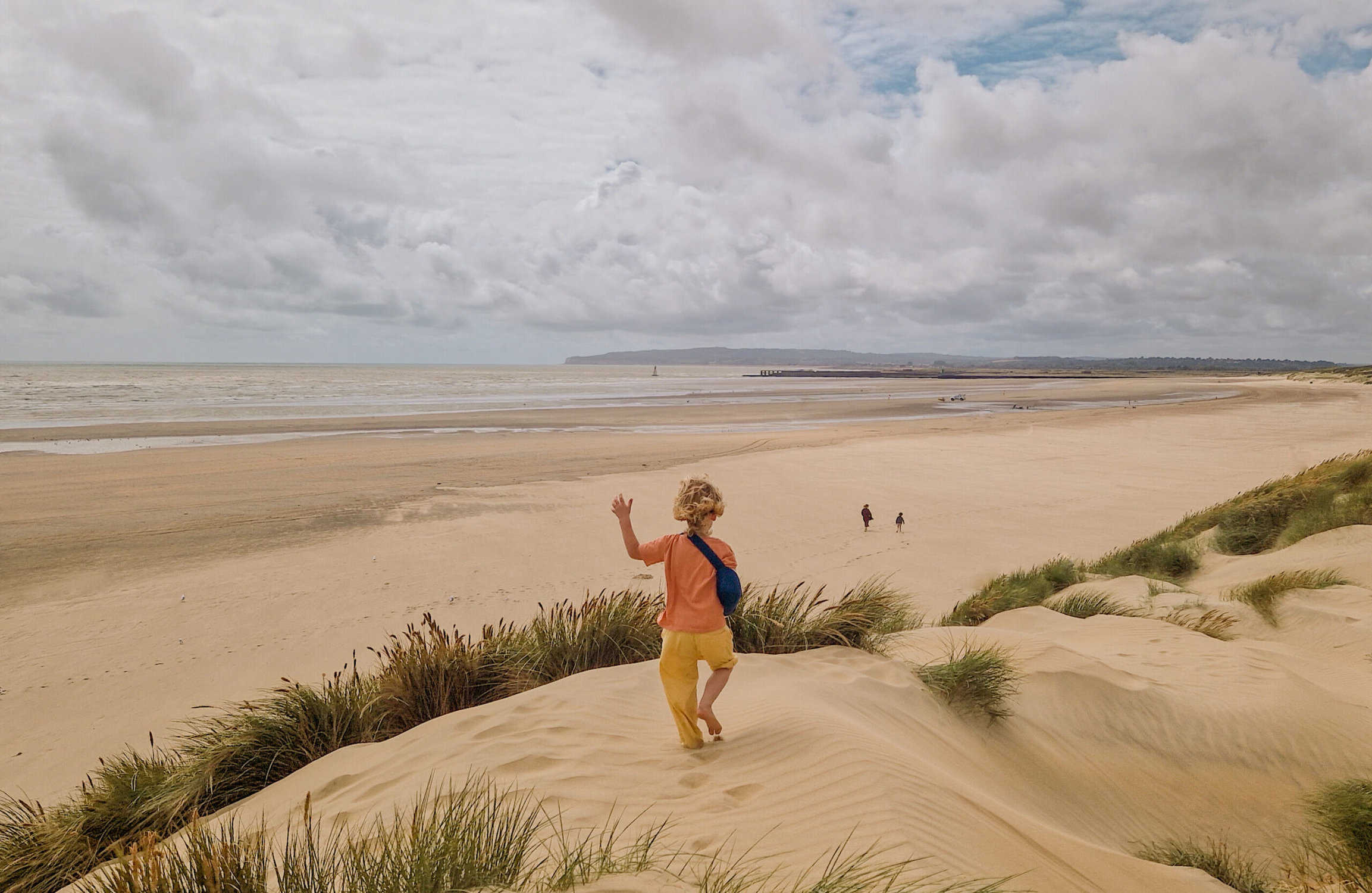 Child playing on sand dunes at Camber Sands beach, UK - best Southern England Beaches for Kids
