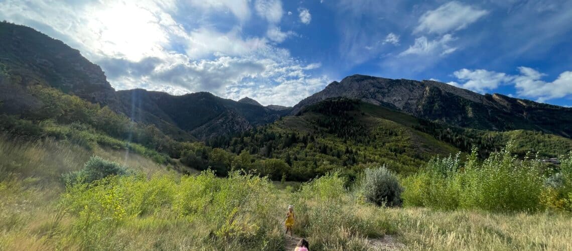 Women's History Month: Adventurers, Activists, and Nature-Lovers. Children on a hiking trail in a green and sunny canyon.