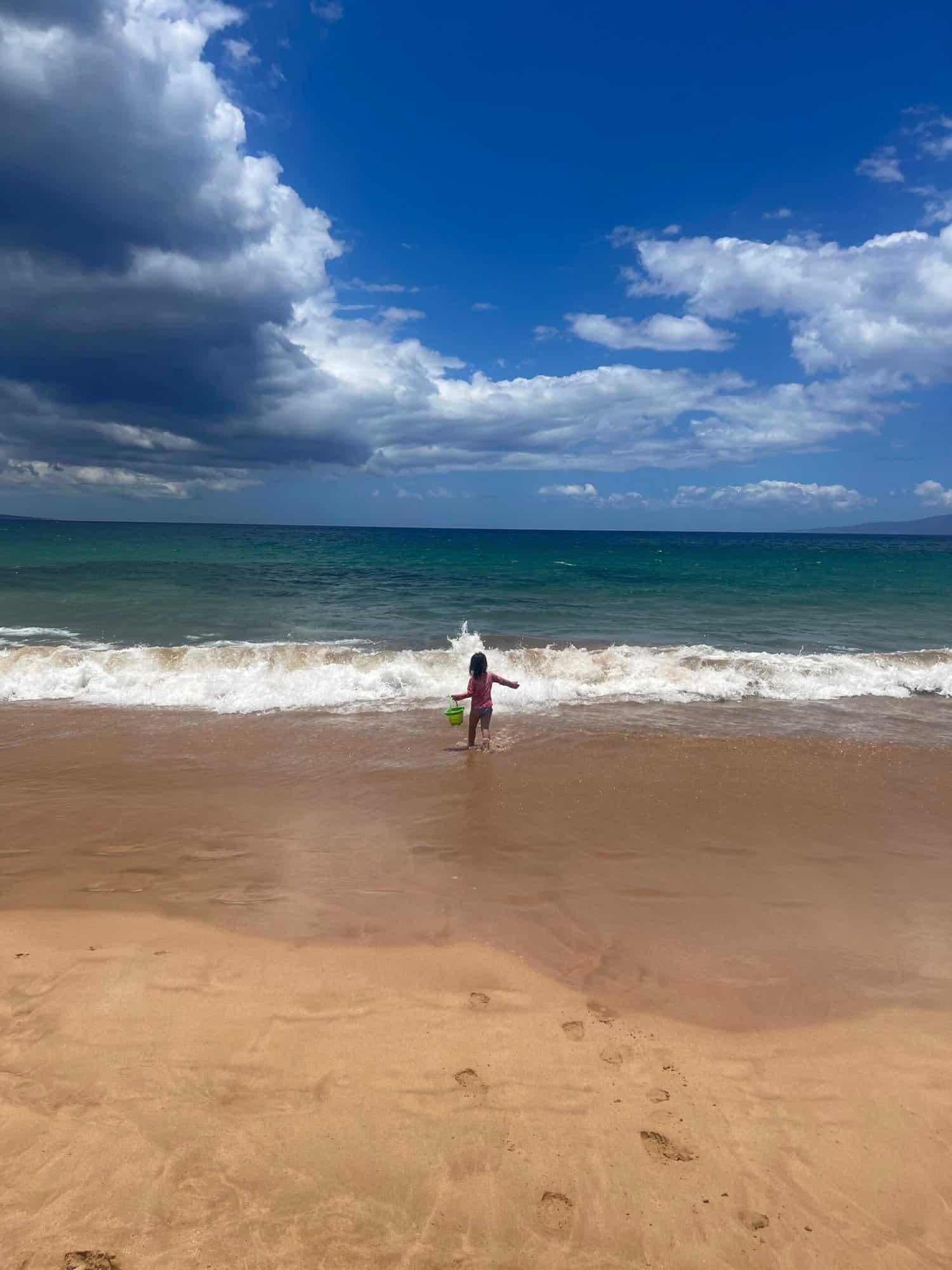 Child on a beach heading into the waves.