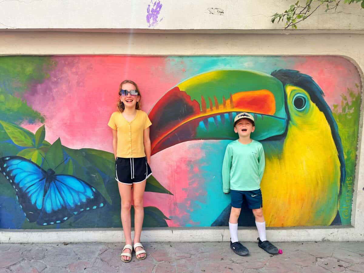 kids standing in front of colorful painted toucan and butterfly mural in San Pedro Belize