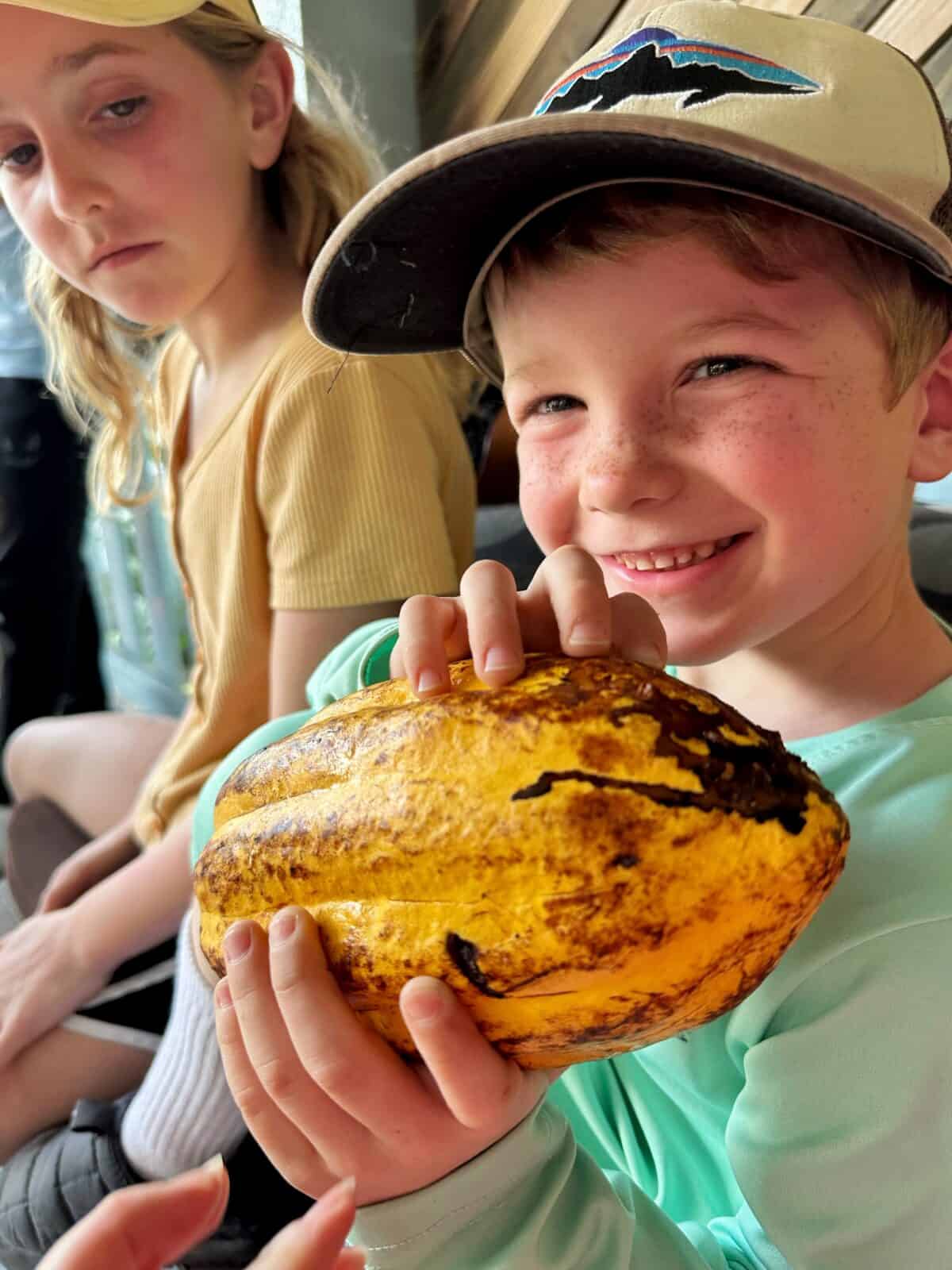 child holding cocoa pod during chocolate class belize