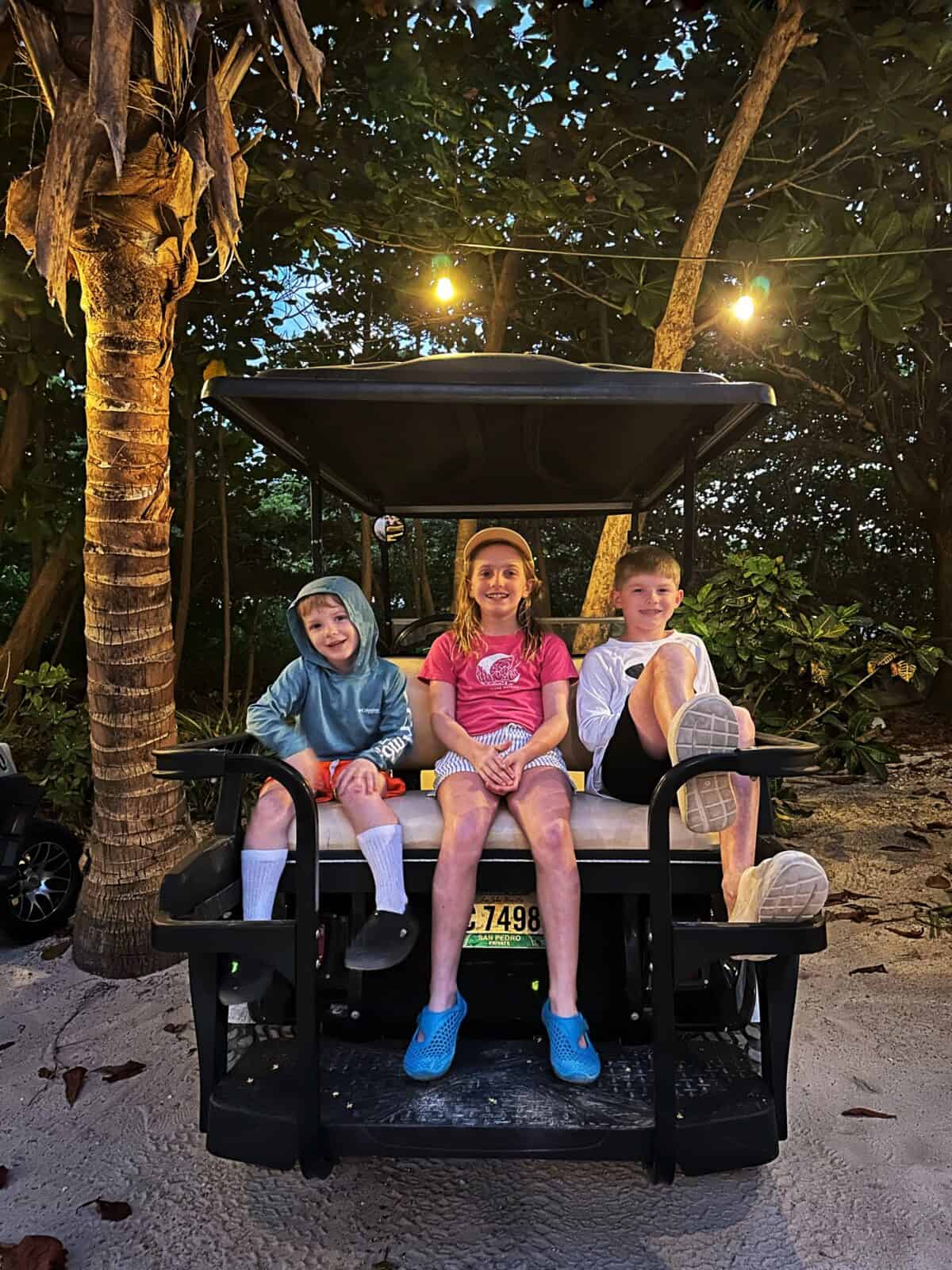 kids in the back of a golf cart exploring ambergris caye and san pedro town