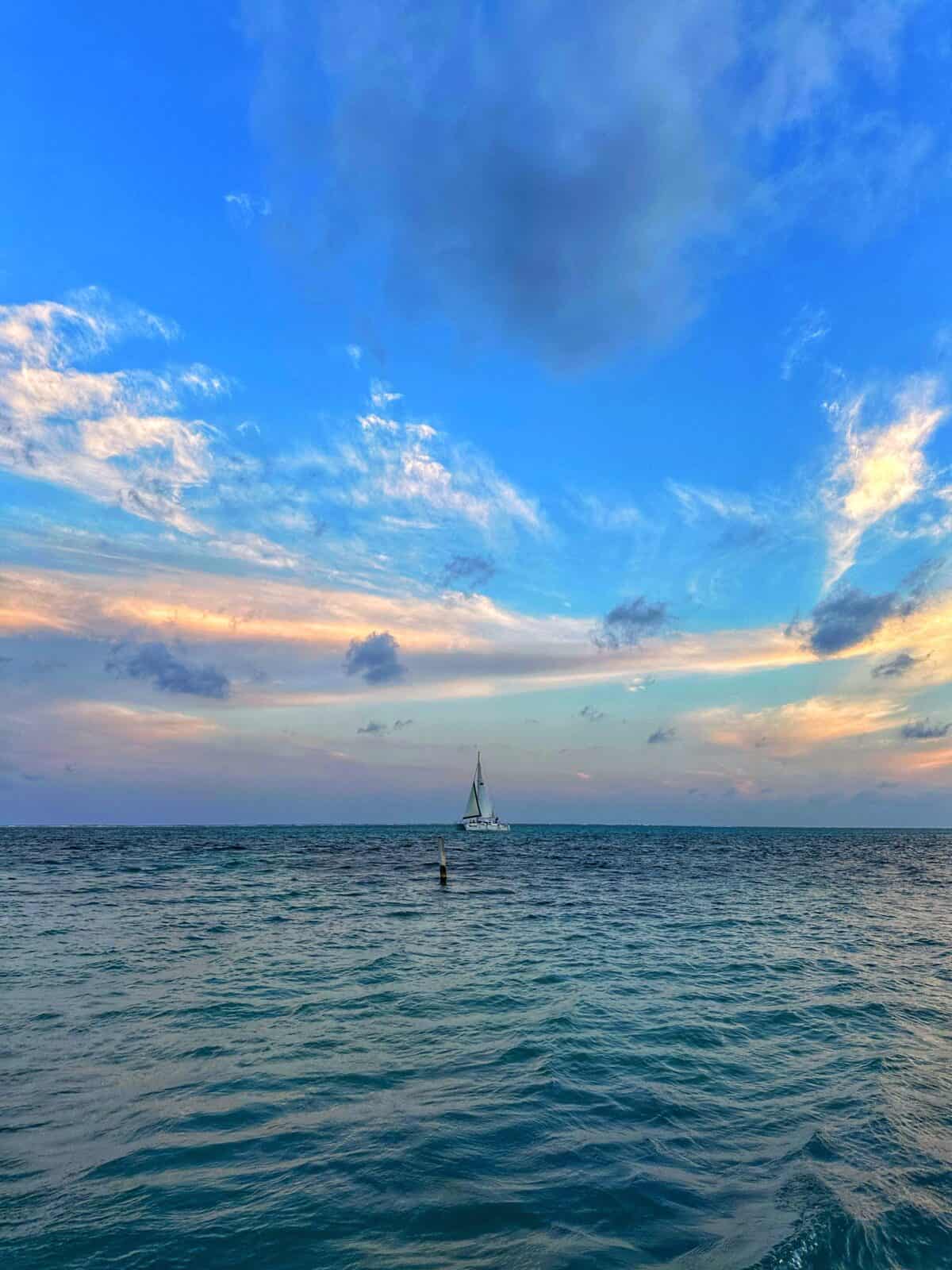 sailboat at sunset on blue waters of the Caribbean Sea in Ambergris Caye Belize